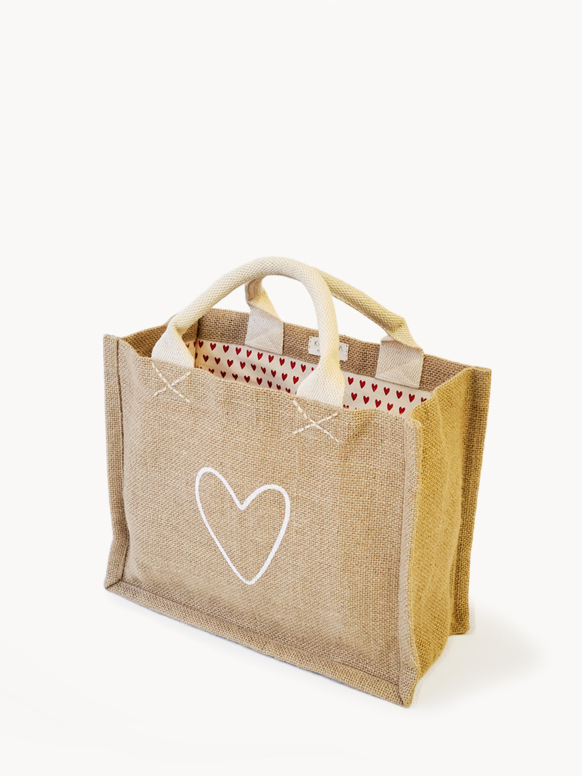 Introducing the "Jute Canvas Gift Bag - Love," a handmade tote bag crafted from burlap with an elegant white heart design on the side. The interior is lined with eco-friendly red and white fabric adorned with small red hearts, offering a perfect blend of style and sustainability.