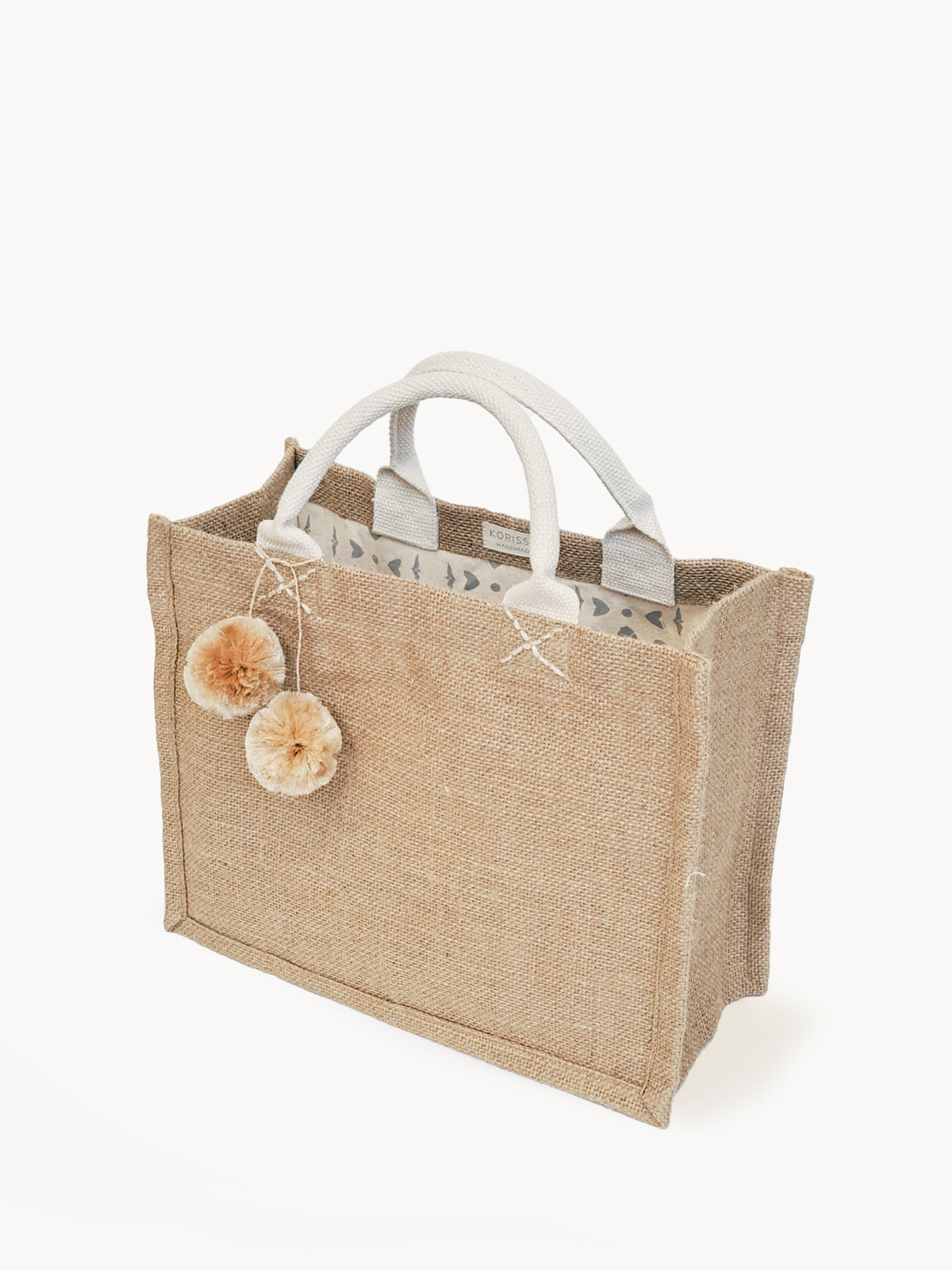 This Jute Canvas Gift Bag with Pompom, handcrafted with attention to detail, features white handles and two beige pom-poms, complemented by a charming patterned lining. Ideal for any fair trade enthusiast, it seamlessly blends style and ethics.