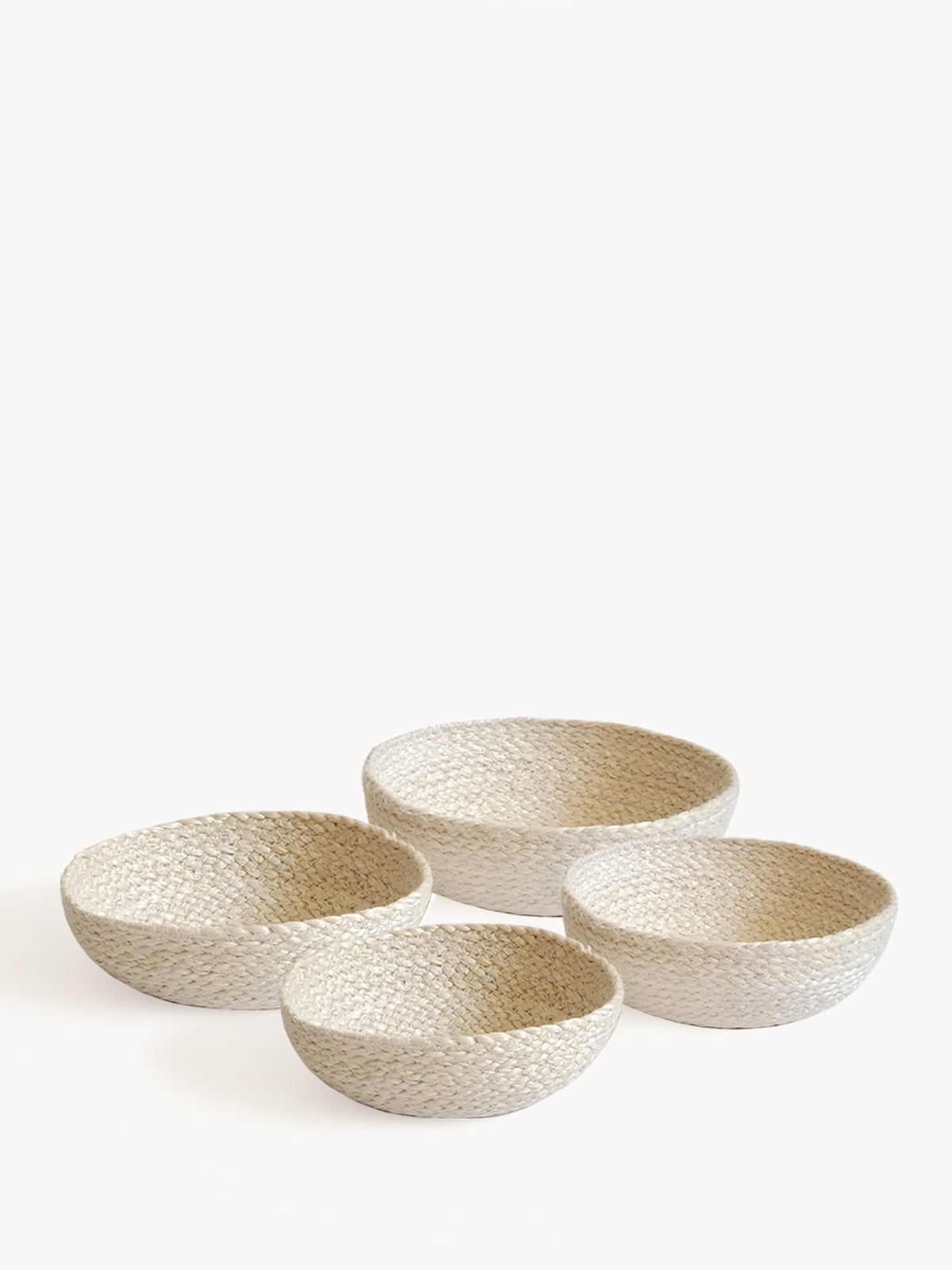 On a flat surface against a plain background, a set of four Kata Candy Bowls in white, crafted by fair trade artisans, is displayed. These versatile woven straw baskets highlight the beauty and authenticity of natural jute.