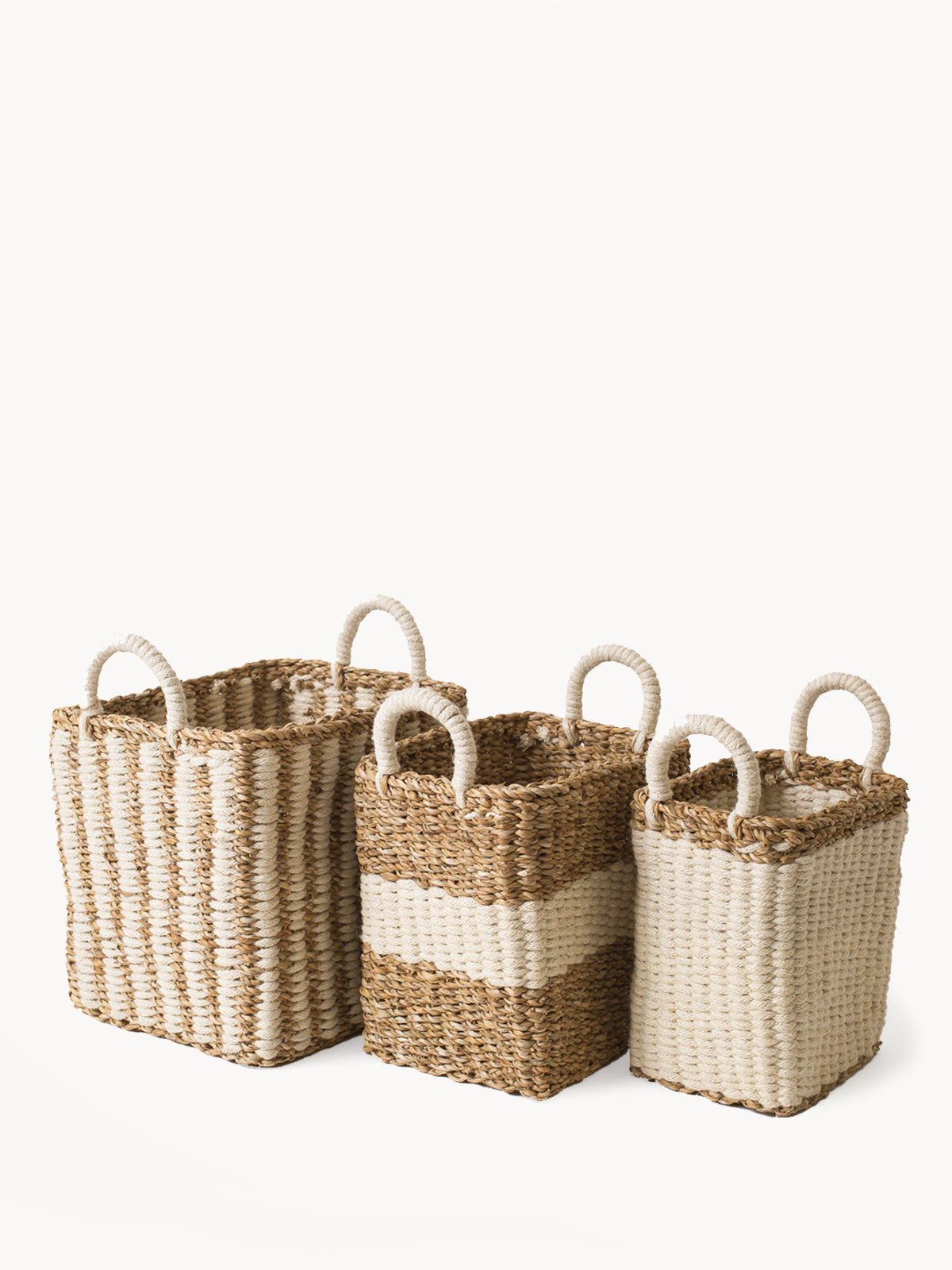 The Ula Storage Baskets, a set of three handmade options with handles in different sizes, are arranged in a row against a plain background. Made from jute wool, these Fair Trade baskets highlight artisanal craftsmanship and sustainable design.