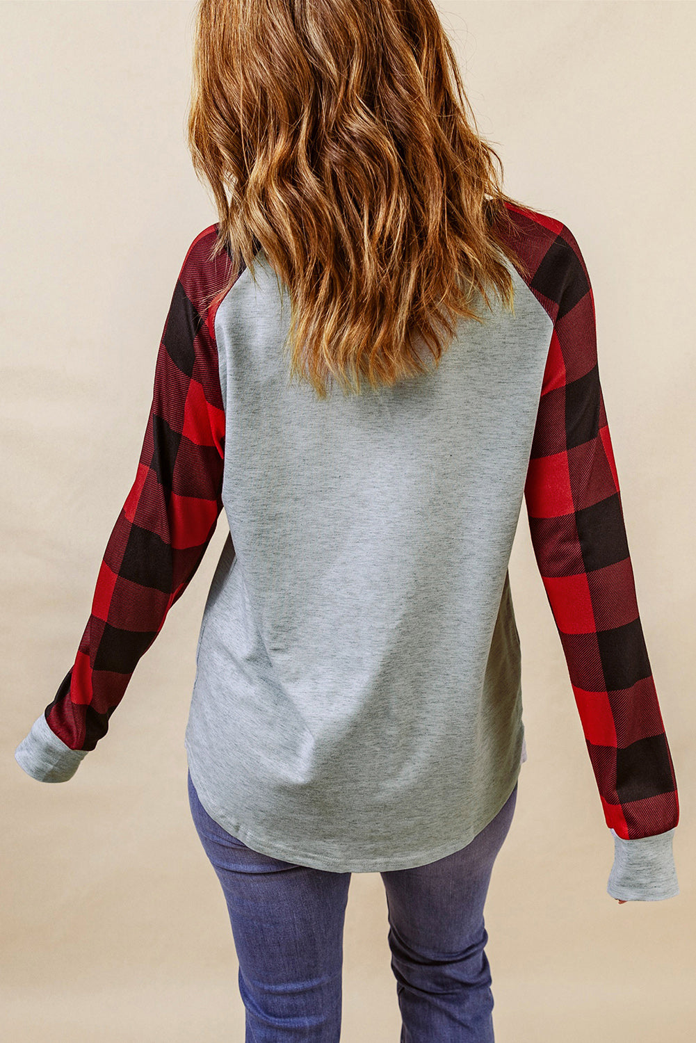 A person with wavy, brown hair is standing with their back to the camera, wearing a Gray Buffalo Plaid Long Sleeve Sweatshirt and blue jeans.