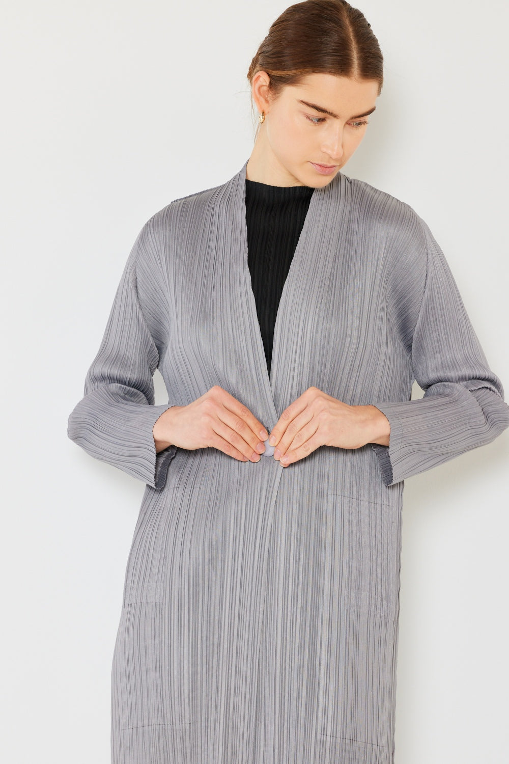 A person wears the Marina West Swim Pleated Long Sleeve Cardigan over a matching top and gray wide-leg pants, standing against a plain light background. This versatile layering piece, with its chic pleated long sleeves, adds an elegant touch to the ensemble.