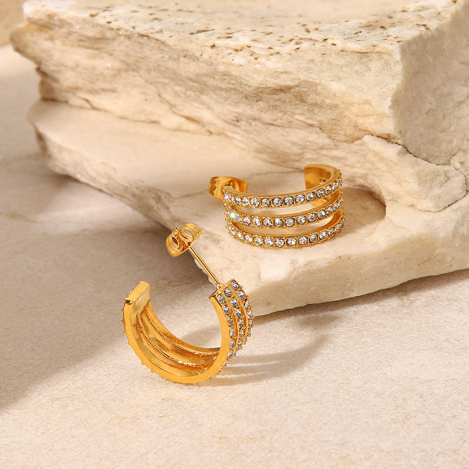 The Stainless Steel Inlaid Zircon C-Hoop Earrings perfectly blend elegance, featuring a triple row of small, clear gemstones on each gold-plated hoop.