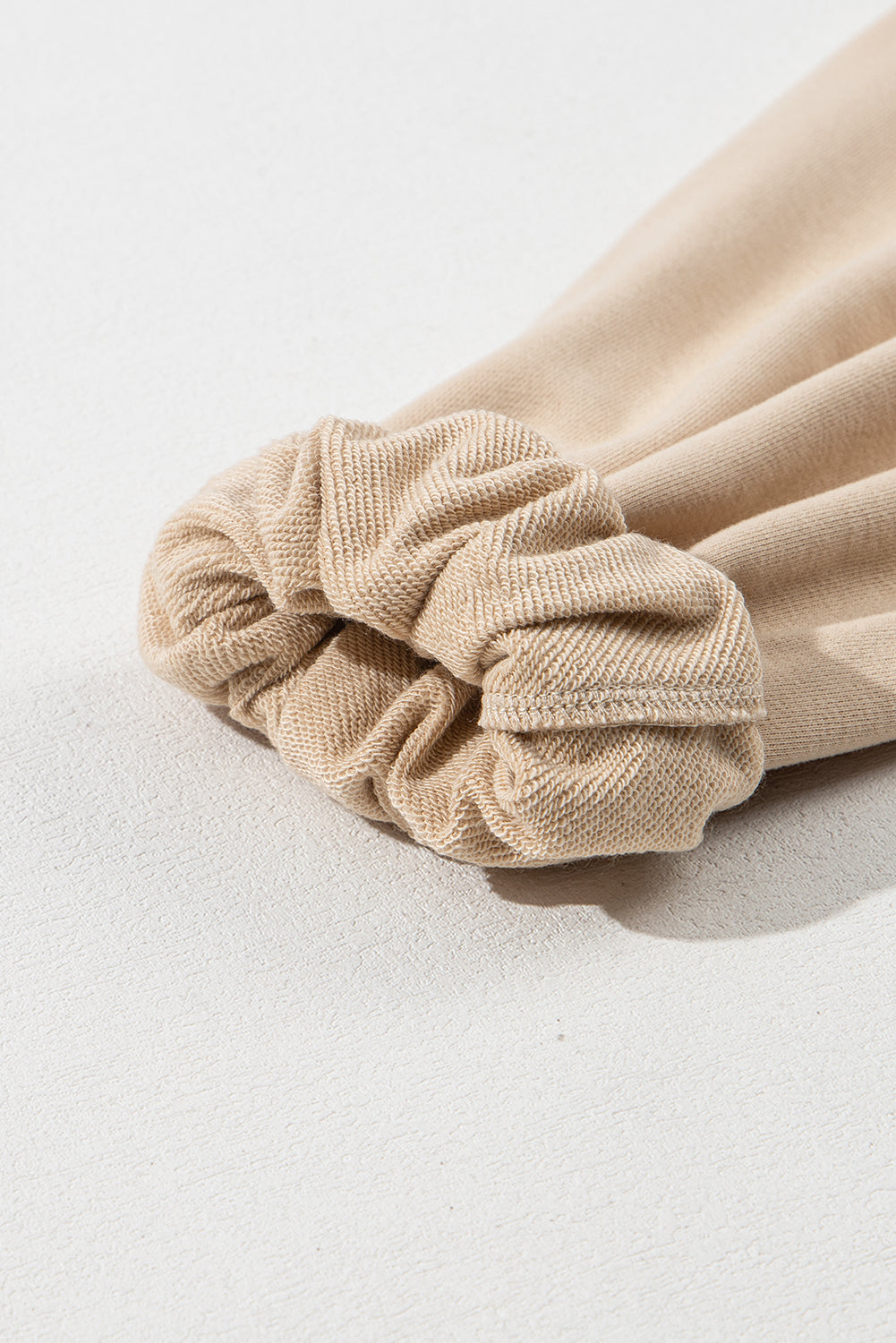 A person with long brown hair is standing with their back to the camera, wearing a Parchment Solid Kangaroo Pocket Half Zipper Oversized Hoodie and black shorts.