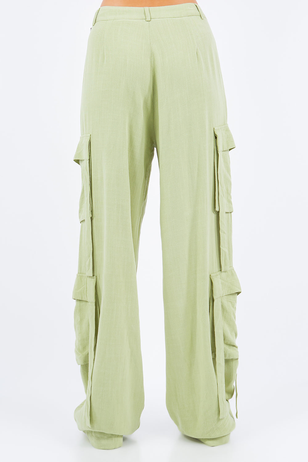 A person is wearing American Bazi light green linen wide leg cargo pants with multiple pockets and white sneakers.