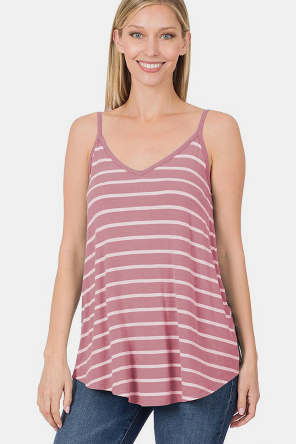 A person with curly hair wearing a chic Zenana Striped Curved Hem Cami in pink and white stands against a plain background, making it perfect for any summer wardrobe.