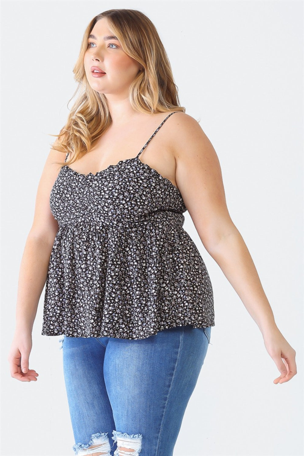 A woman stands facing the camera wearing a Zenobia Plus Size Frill Smocked Floral Sweetheart Neck Cami with dark jeans, against a plain background.