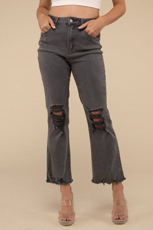 Person wearing acid washed high waist distressed straight pants and beige sandals against a neutral background.