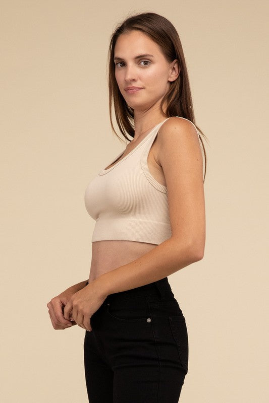 A person with long brown hair wearing the Ribbed Seamless Crop Top in light blue and black pants stands against a beige background, showcasing a perfect summer essential.