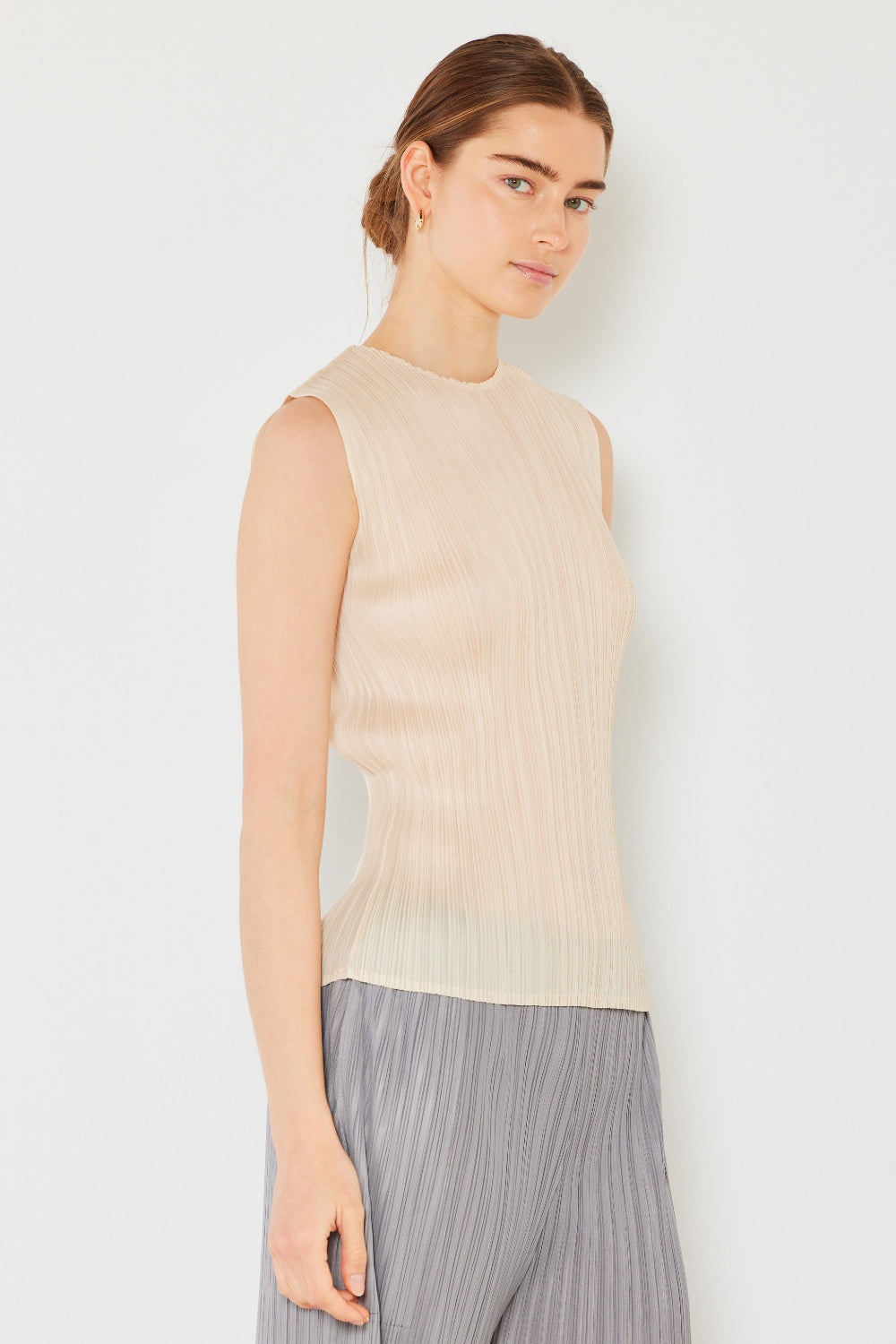 Person wearing a Marina West Swim Pleated Sleeveless Crewneck Tank and a gray pleated skirt, standing against a white background.