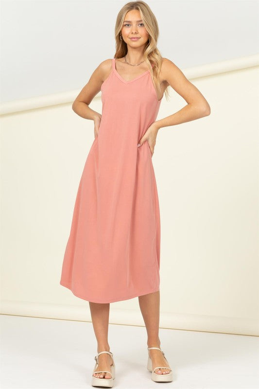 A person in the Make It Right Sleeveless Maxi Dress, known for its relaxed fit and pink hue, poses gracefully against a plain background.