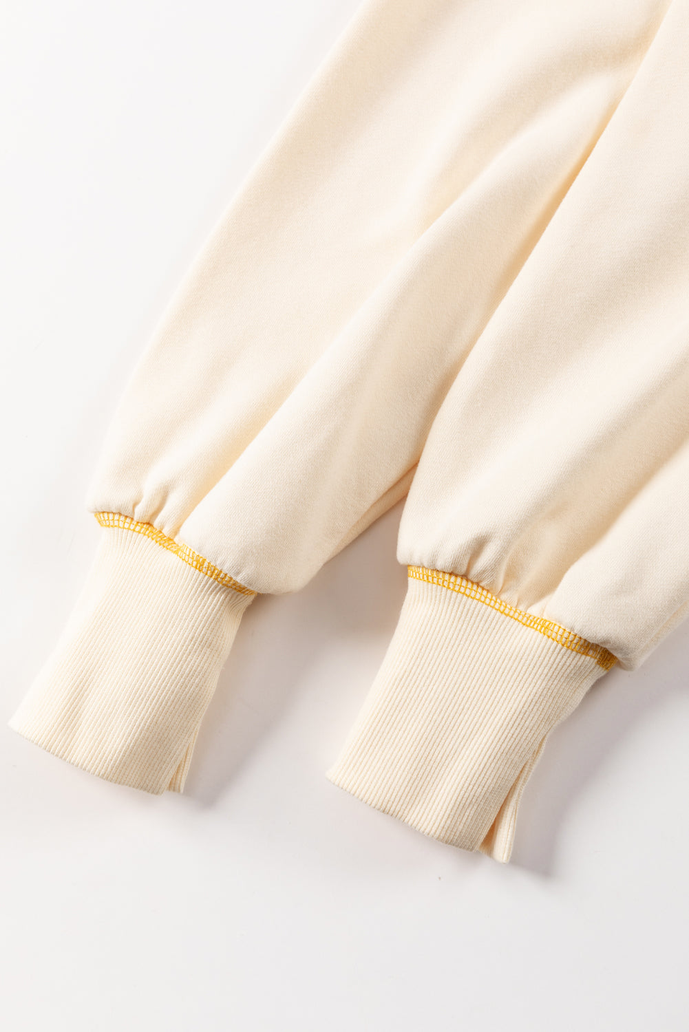 A woman with blonde hair is facing away, wearing a Contrast Stitching Split Baggy Sweatshirt. She stands in a room adorned with plants and wooden furniture in the background.