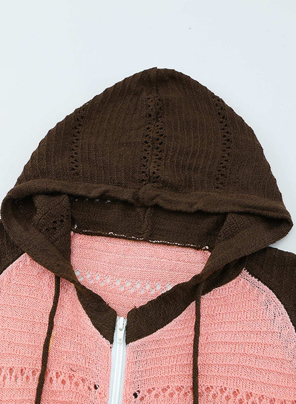 A person wearing the Brown Zipped Front Colorblock Hollow-out Knit Hoodie, featuring a multi-colored striped design with alternating bands of brown, pink, white, and gray. Seen from the back, the sweater showcases the hood and finely knitted texture. The person has long wavy hair—a perfect look for a bonfire on the beach.