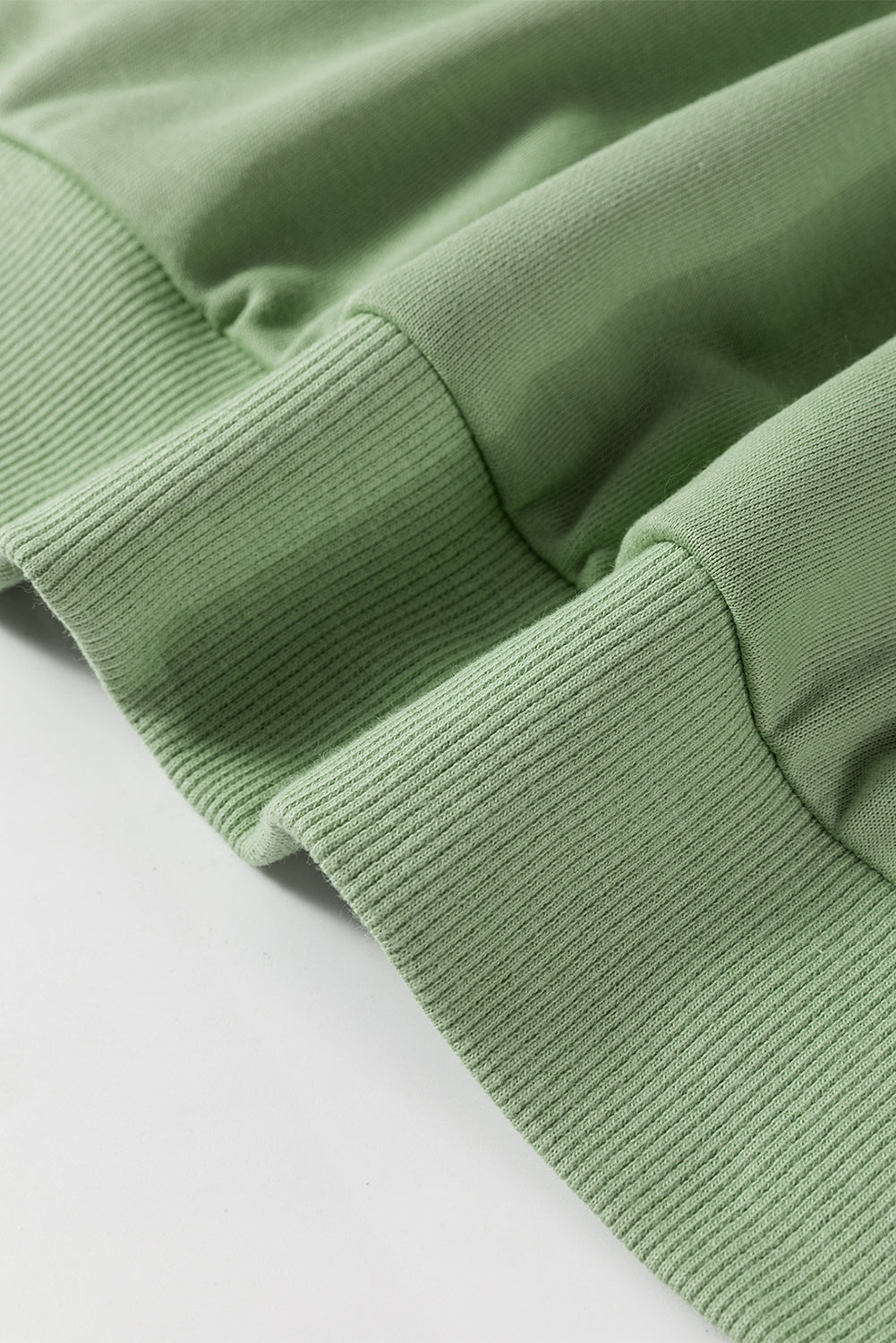 A person wearing a Grass Green Leopard Print Colorblock Raglan Sleeve Sweatshirt stands in front of a brick wall.