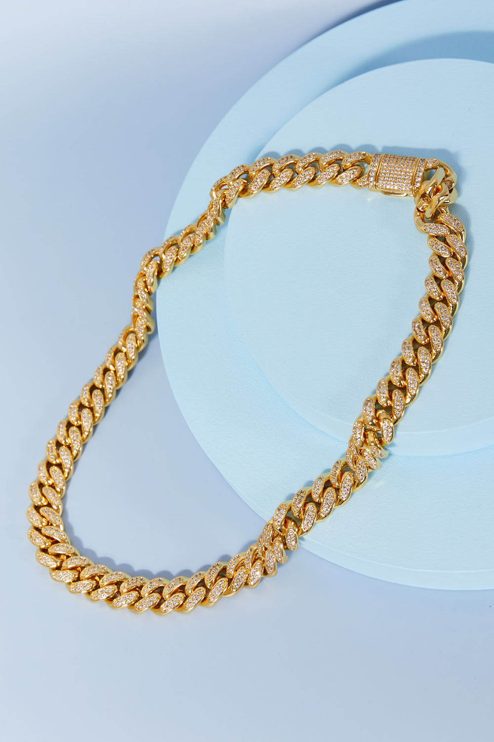 Brass Curb Chain Necklace elegantly displayed on a light blue round surface.