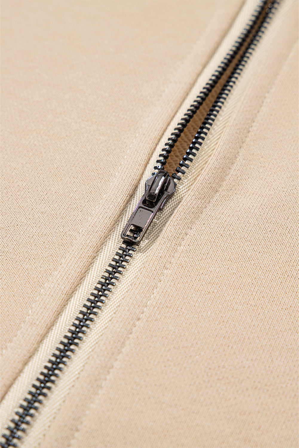 A person with long brown hair is standing with their back to the camera, wearing a Parchment Solid Kangaroo Pocket Half Zipper Oversized Hoodie and black shorts.