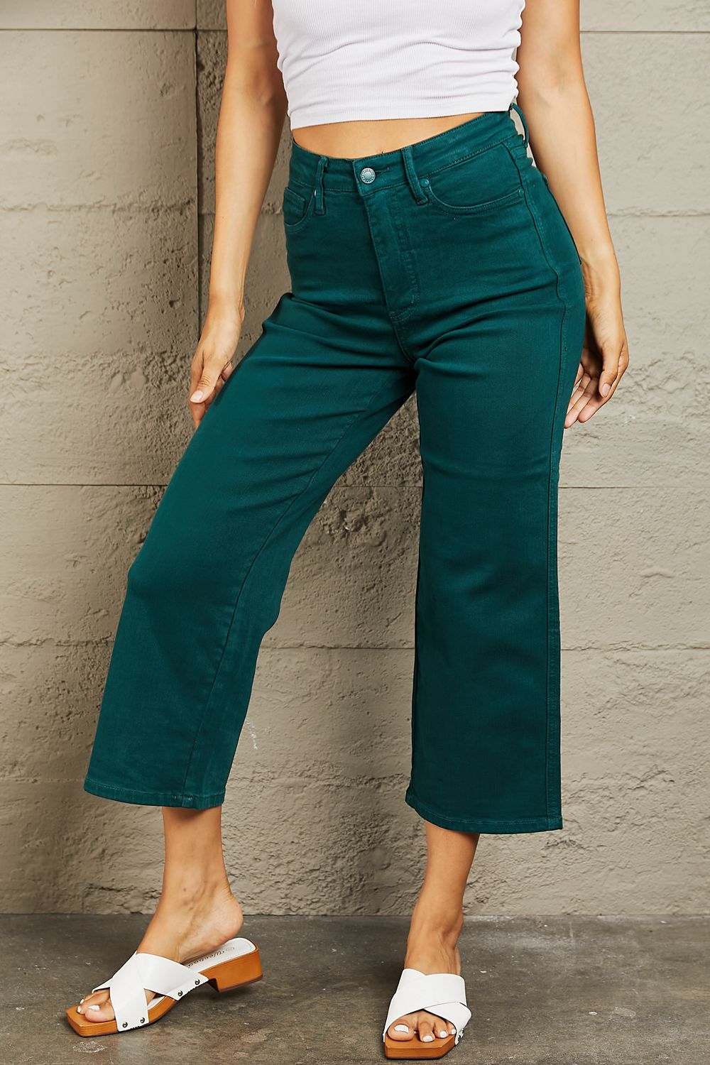 Person wearing Judy Blue Hailey Full Size Tummy Control High Waisted Cropped Wide Leg Jeans that offer subtle silhouette enhancement, paired with stylish white sandals.