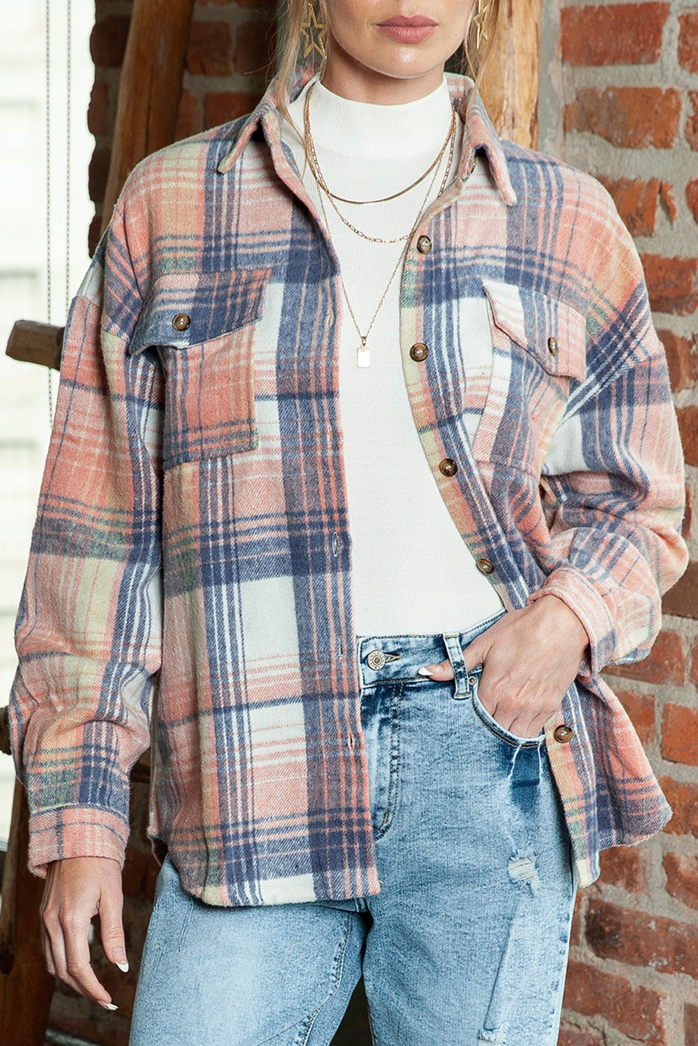A woman wearing a white top, blue jeans, and the Gold Flame & Grey Plaid Button Up Collared Flannel Shacket smiles while posed outdoors.