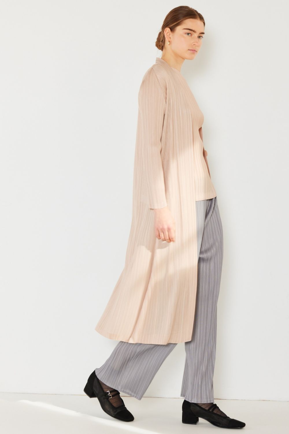 A person wears the Marina West Swim Pleated Long Sleeve Cardigan over a matching top and gray wide-leg pants, standing against a plain light background. This versatile layering piece, with its chic pleated long sleeves, adds an elegant touch to the ensemble.