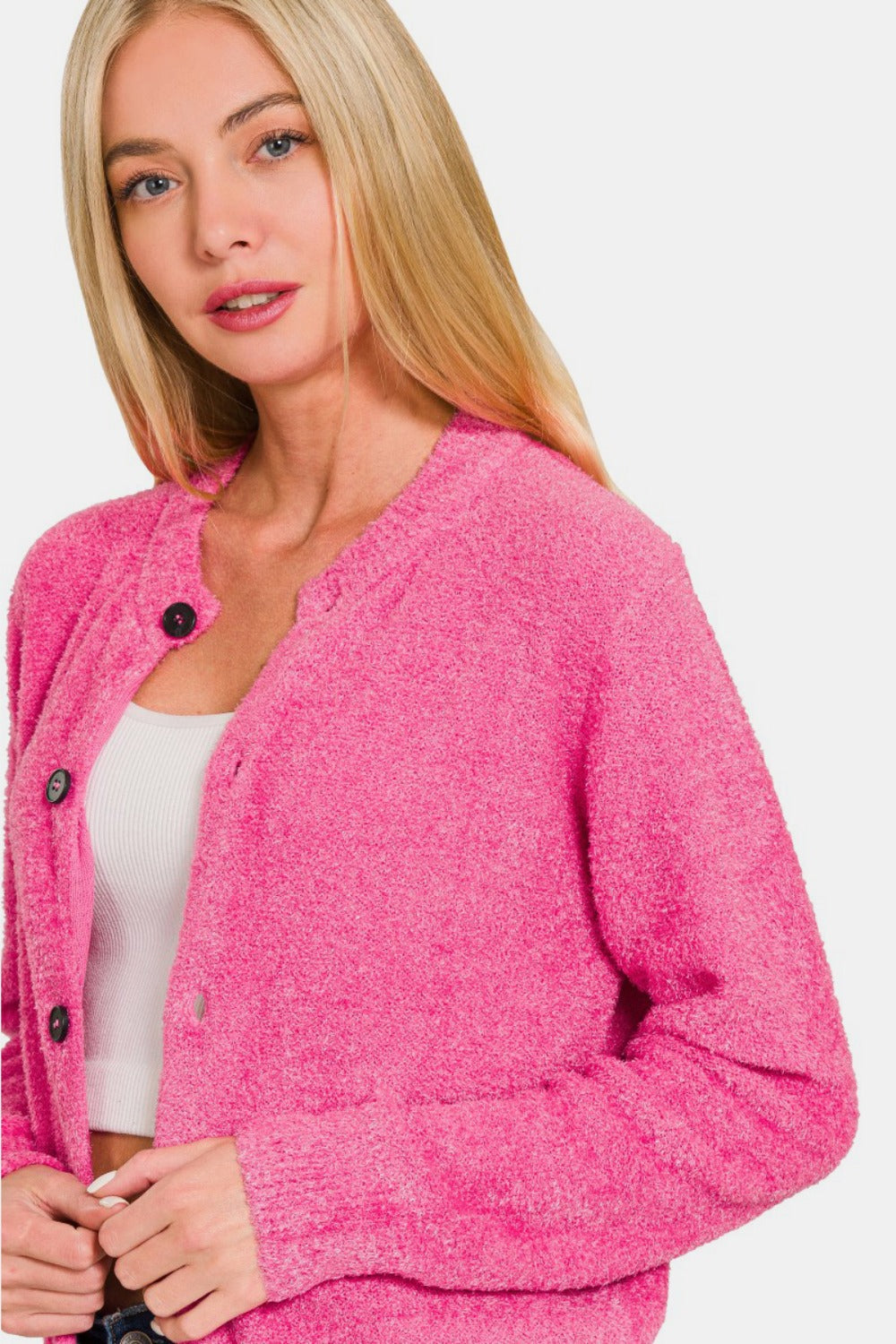 A person with long blonde hair wears a Zenana Button Down Long Sleeve Sweater Cardigan in bright pink and dark blue jeans, posing against a plain white background.