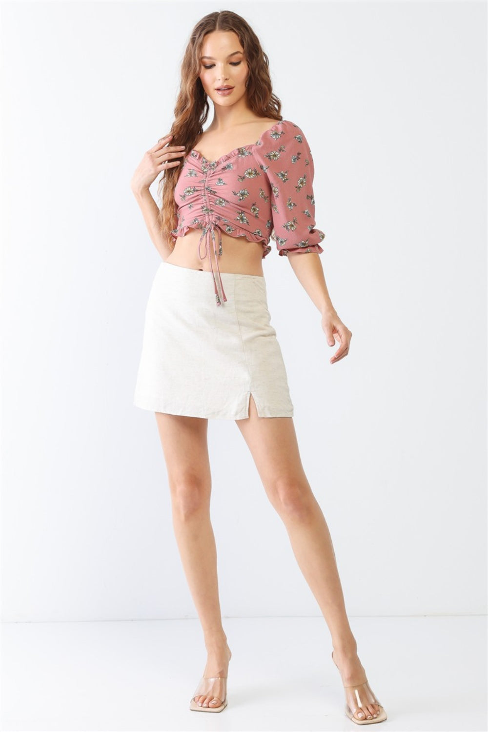 Person wearing the Miss Love / Kevin Co. Floral Ruffle Smocked Back Ruched Crop Top in pink, paired with a cream skirt, posing gracefully against a neutral background.