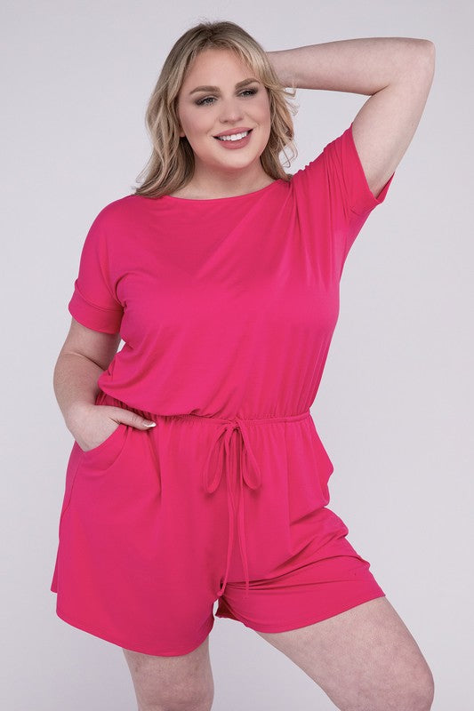 A person is wearing the Plus Brushed DTY Romper with Pockets in bright pink, smiling as they pose with one hand on their head and the other tucked into a pocket, all set against a gray background.