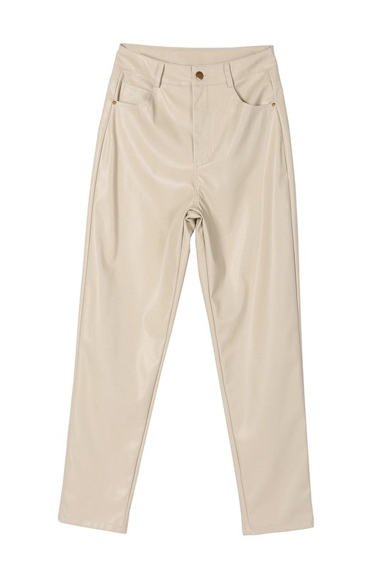 A person wearing a white sweater and black Vegan leather pants with hands in the pockets.