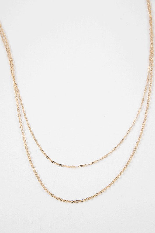 The Othello Layered Necklace is a refined piece crafted from 14k gold-plated stainless steel, featuring a double-layered chain design with a lobster clasp and adjustable length.