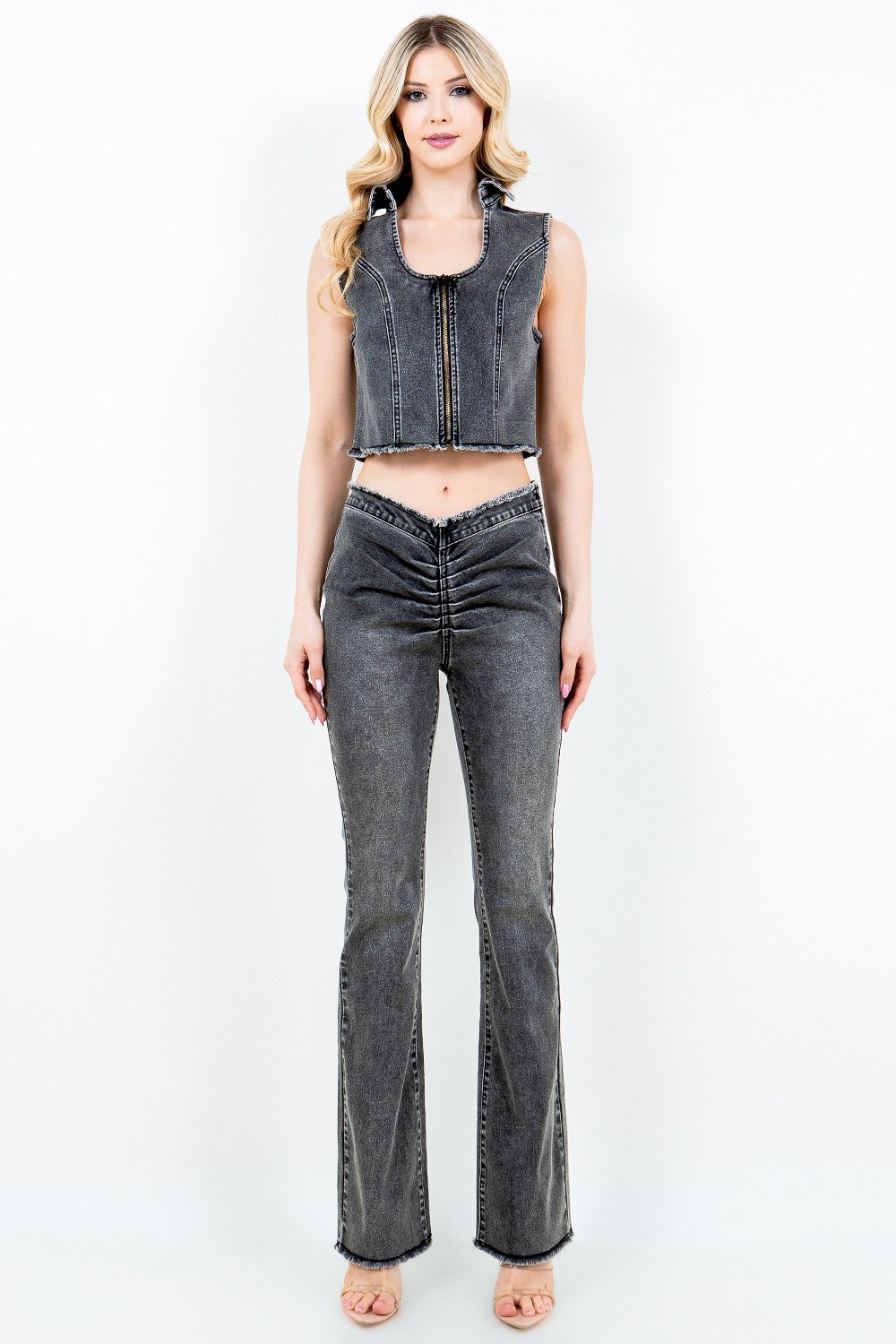 A person wearing American Bazi V-Cut Ruched Flare Pants in gray denim with a high-waisted design and an unfinished hem, standing against a plain background.