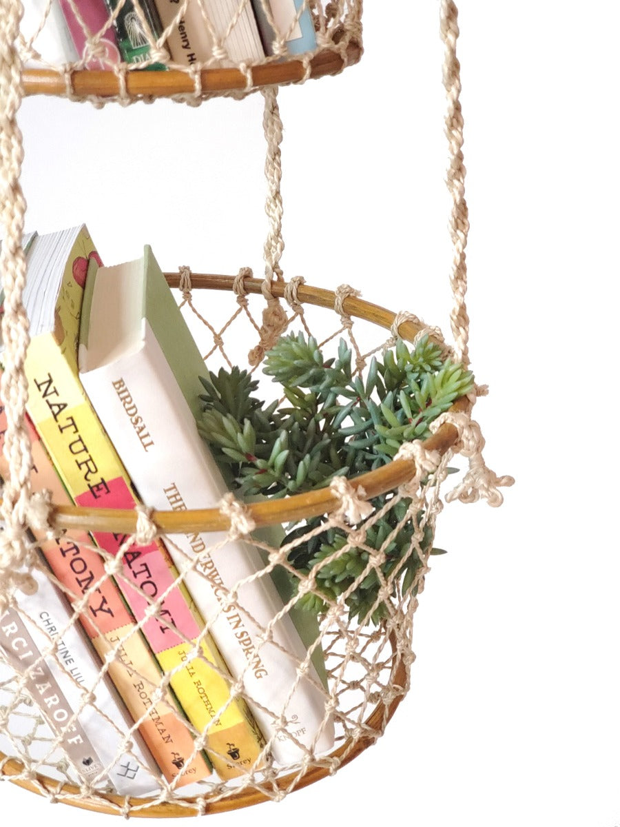 The Jhuri Double Hanging Basket is a macramé plant holder with two intricately woven baskets, each holding a lush green plant. Created by Fair Trade artisans, this piece showcases sustainably handmade craftsmanship and timeless elegance against a simple backdrop.