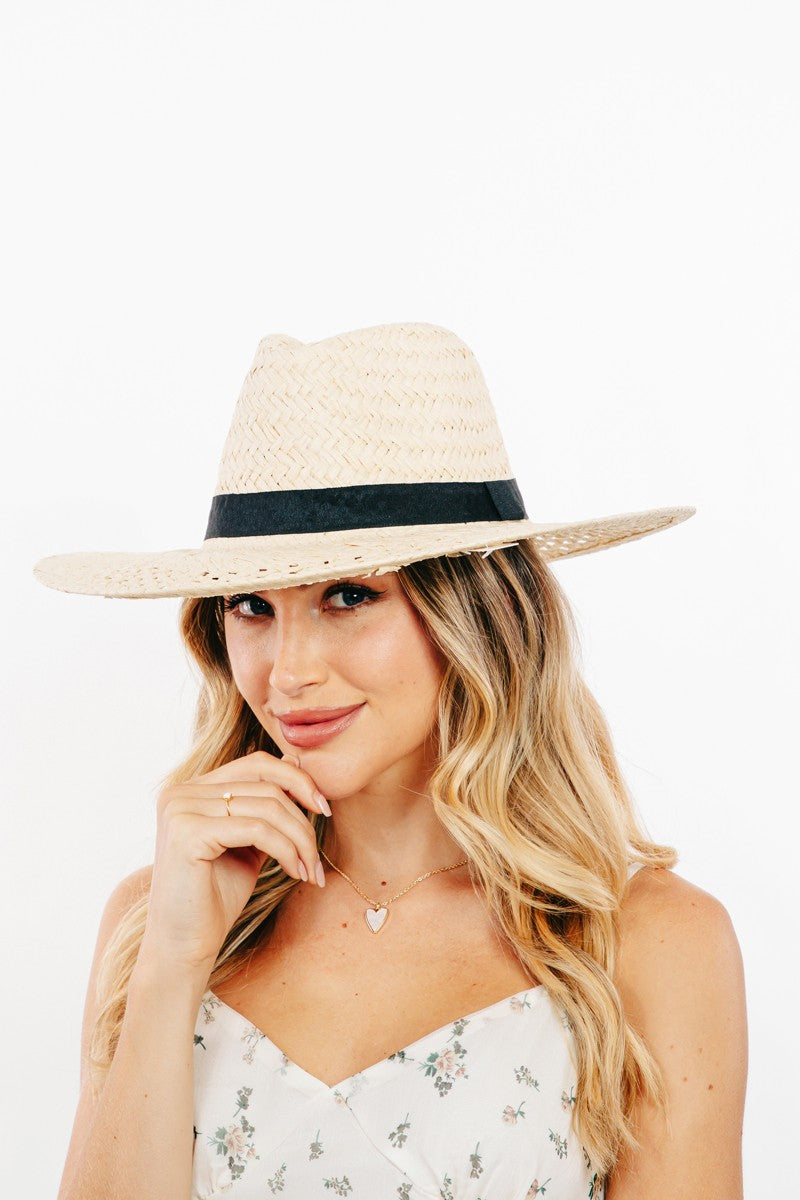 The Fame Basket Weave Straw Sun Hat, featuring a black band and ideal as a fashion accessory, is showcased on a clear stand against a white background.