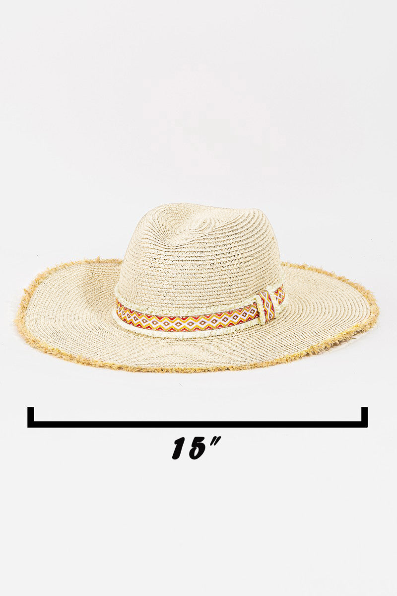 The Fame Geometric Raw Hem Hat is a stylish wide-brimmed straw hat, adorned with a red and beige geometric patterned band, making it the perfect fashionable accessory.