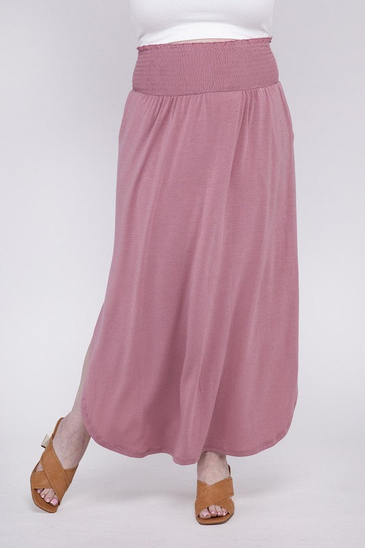 A person wearing a white top and the Plus Smocked Waist Side Slit Maxi Skirt w/ Pockets stands with crossed legs, showcasing tan heels.