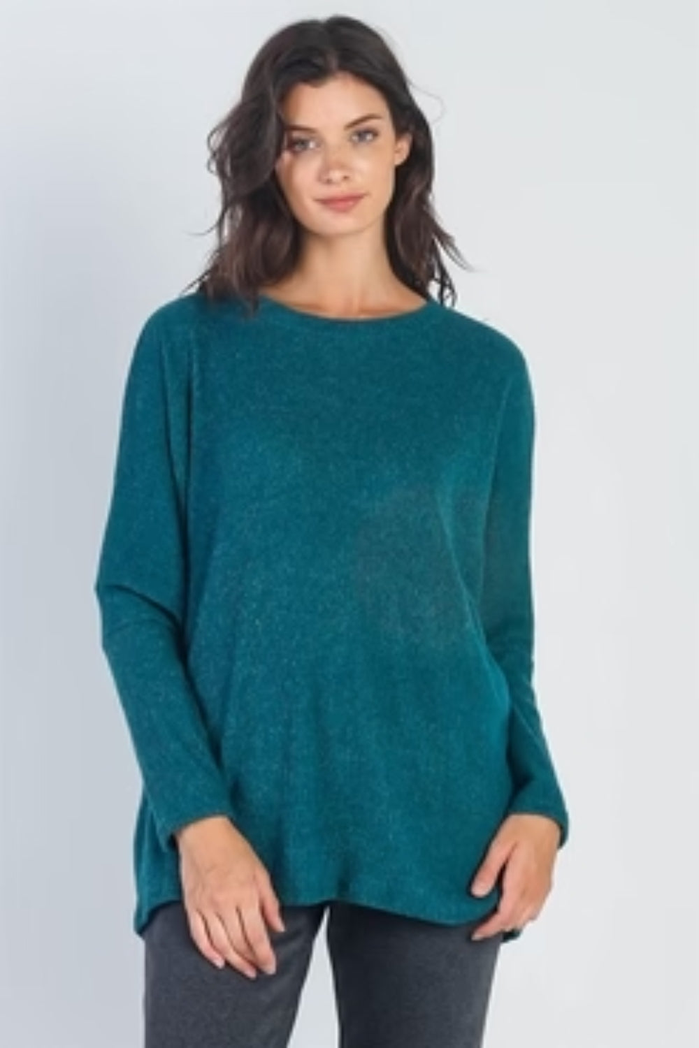 A person stands in front of a plain background wearing the Cherish Apparel Round Neck Long Sleeve Sweater in teal, dark gray pants, white socks, and beige slide sandals—a classic wardrobe staple.