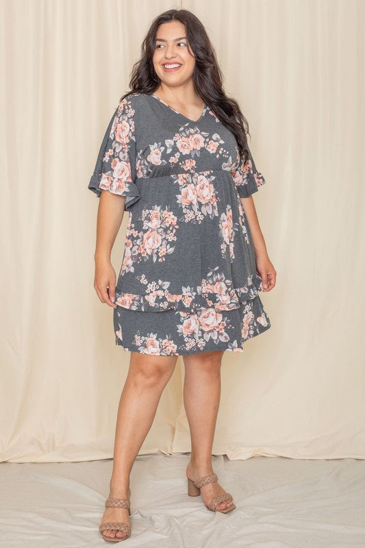 A woman wearing a Floral V Neck Ruffle Dress stands indoors, posing with one hand on her hip.