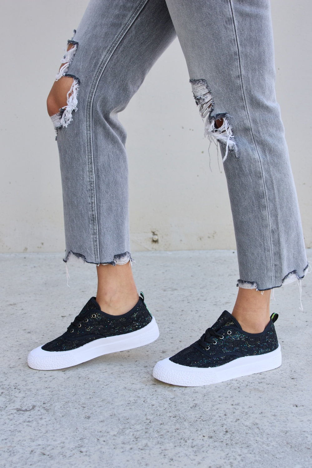 Person wearing ripped gray jeans and Forever Link Sequin Lace-Up Platform Sneakers.