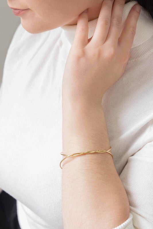 A delicate Twister Cuff Bracelet on a pale surface.