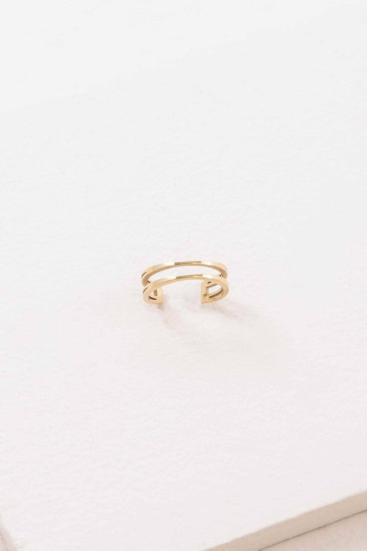 This minimalist jewelry piece, aptly named "Double the Gold Ear Cuff," is crafted from 14K gold over stainless steel and showcases a sleek double band design. Elegantly placed on a white surface, it embodies the simple sophistication of a golden open cuff ring.