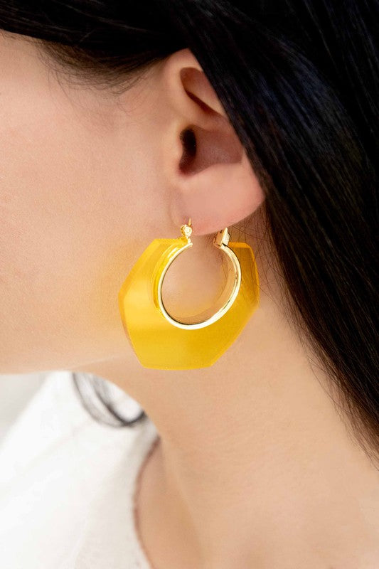 A pair of Angled Clear Hoop Earrings displayed on a white surface.