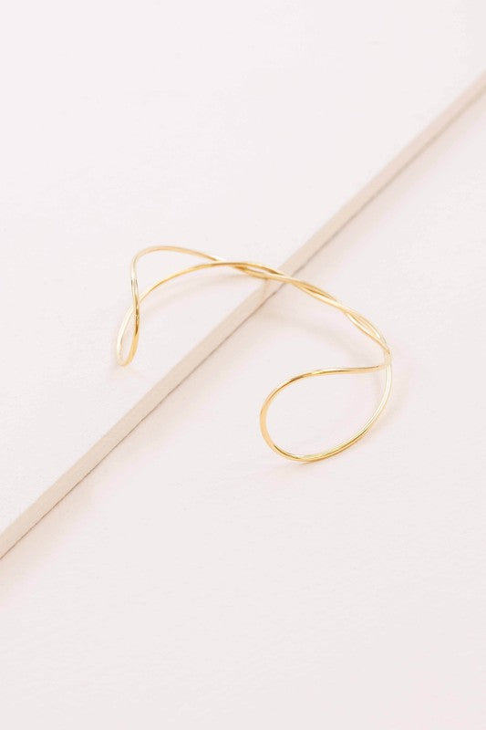 A delicate Twister Cuff Bracelet on a pale surface.