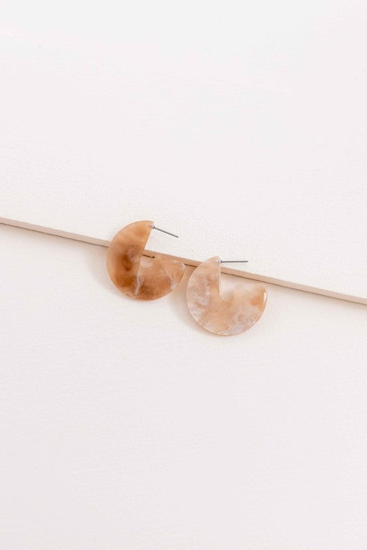 A pair of Marble Half Hoop Earrings displayed against a light pink background.