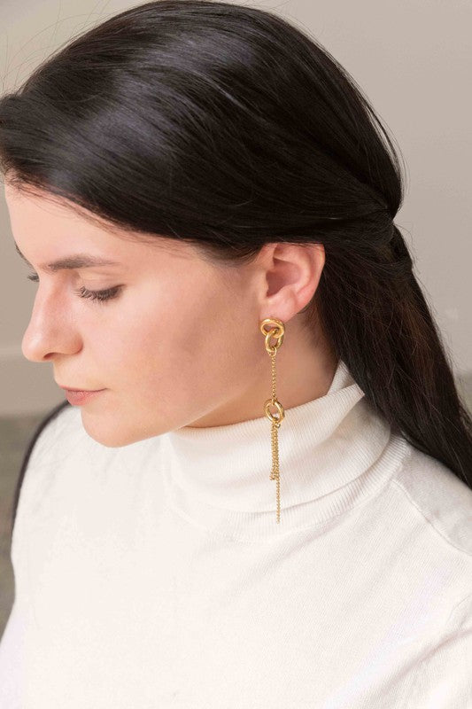 Asymmetrical circle drop earrings with chain and hoop design displayed on a white surface.