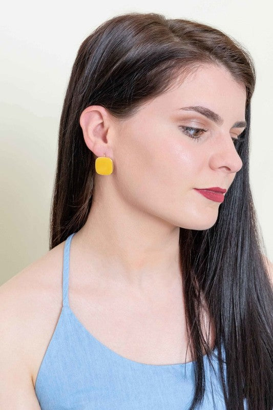 The On the Go Hook Earrings 14K, a pair of square, yellow earrings with 14K gold plate trim, rest on a white surface, bringing a hint of casual style with their elegant yet understated design.