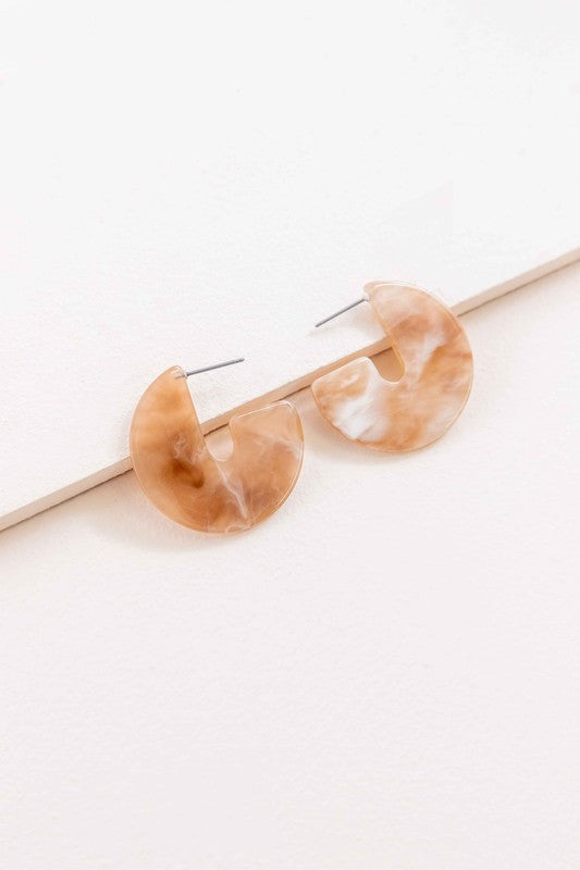 A pair of Marble Half Hoop Earrings displayed against a light pink background.
