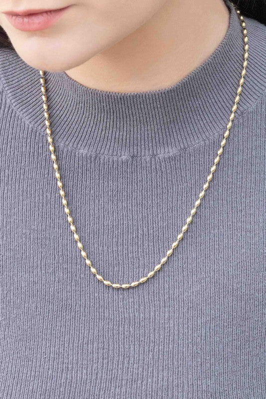 The Gold Beaded Chain Necklace, crafted in 14k gold with intricate details, is elegantly photographed against a white background.