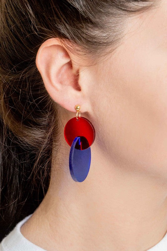 A pair of Clear Color Pop drop earrings with a pop of red accents displayed on a white surface.