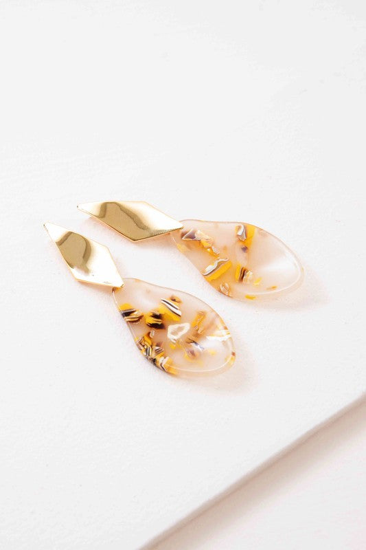 A pair of Yellow Drip dangle earrings with floral inclusions on a white background.