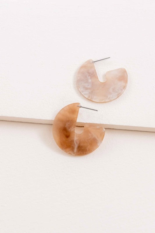 A pair of Marble Half Hoop Earrings displayed against a light pink background.