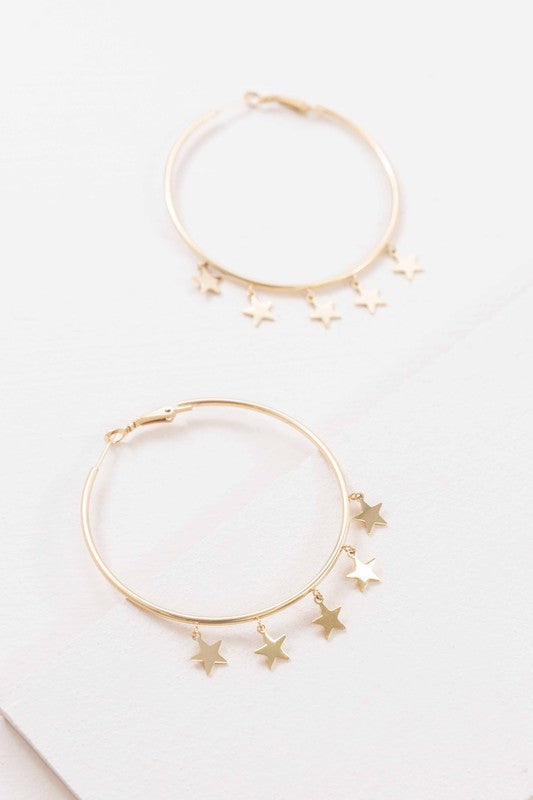 A pair of Night Dreamer Hoop Earrings with celestial star charms on a white background.