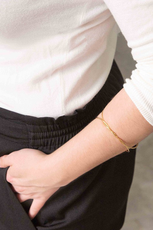 A delicate Twister Cuff Bracelet on a pale surface.